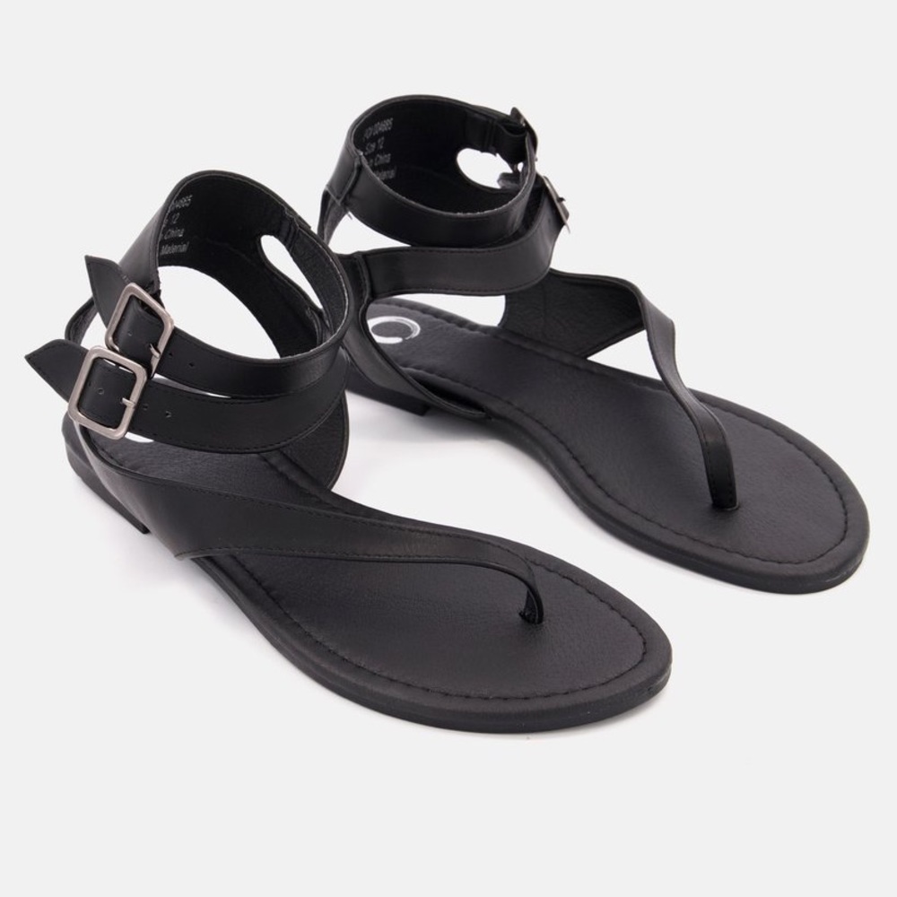 Dual buckle details top this asymmetrical vegan leather strappy sandal